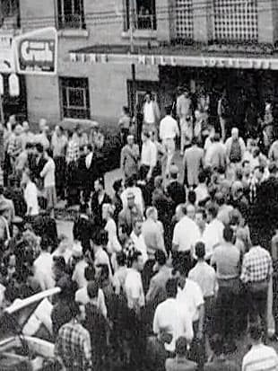 A black-and-white photo of a large crowd gathered outside 19 Regent Street.